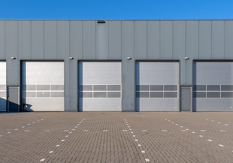 Row of grey industrial Units with roller shutter doors.