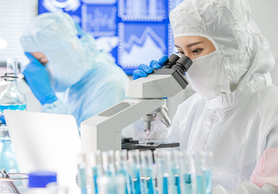 asian biotechnology research team look microscope with cleanroom clothes and conduct experiments in the laboratory